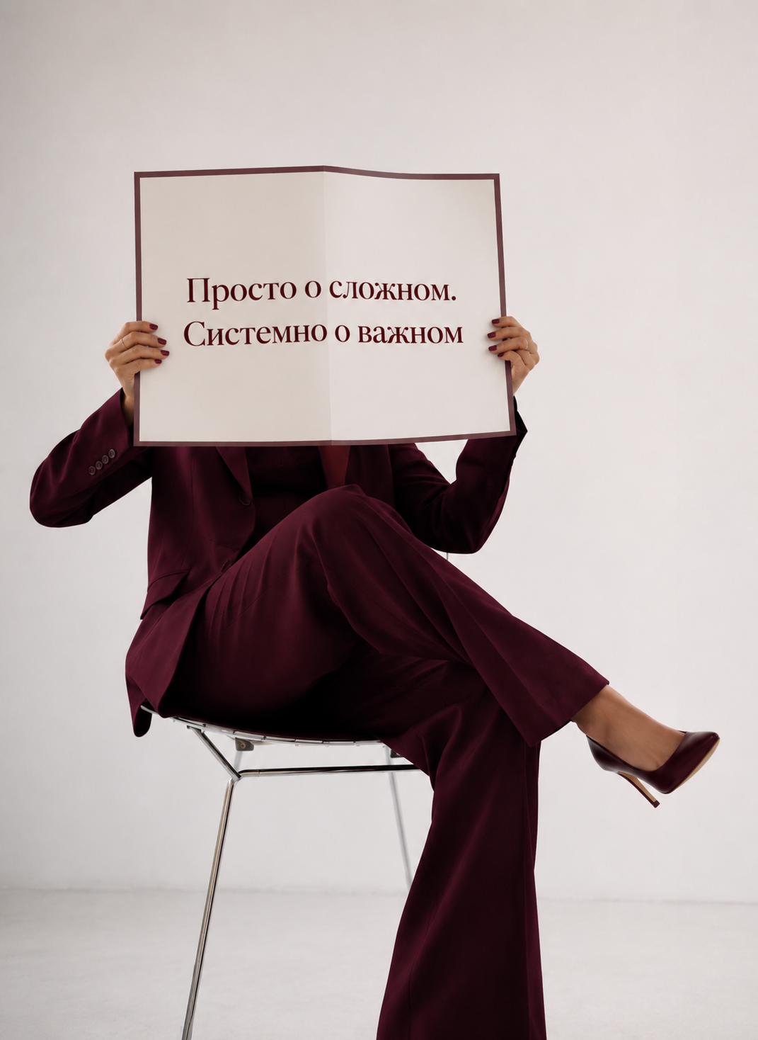 Женщина в бордовом костюме держит раскрытый документ с фразой о системном подходе
